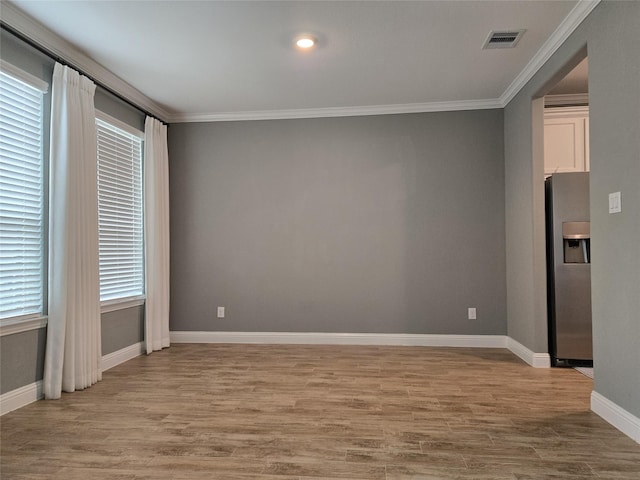 unfurnished room featuring ornamental molding and light hardwood / wood-style flooring