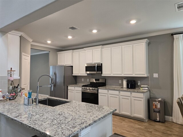 kitchen featuring appliances with stainless steel finishes, kitchen peninsula, light stone countertops, white cabinets, and sink