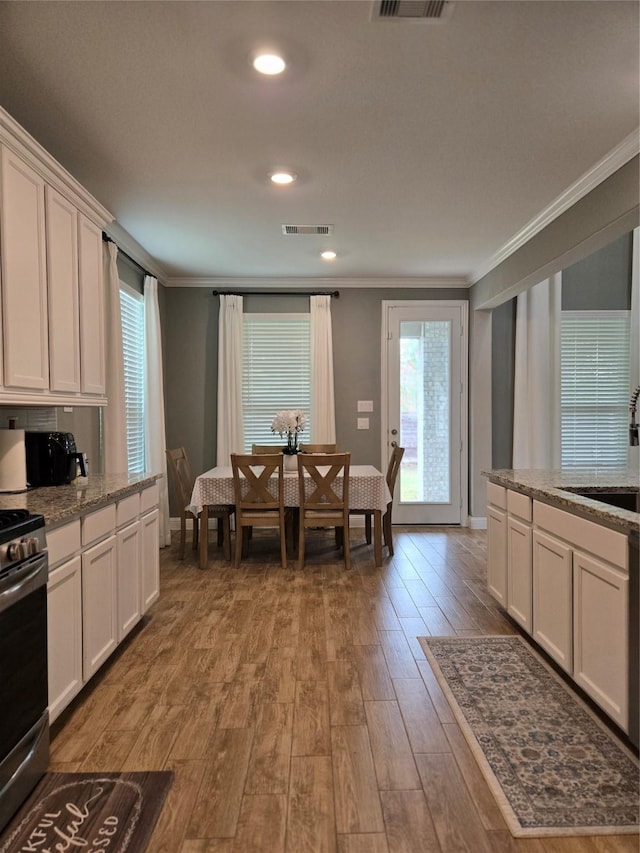 kitchen featuring white cabinets, stainless steel range oven, light hardwood / wood-style flooring, and crown molding