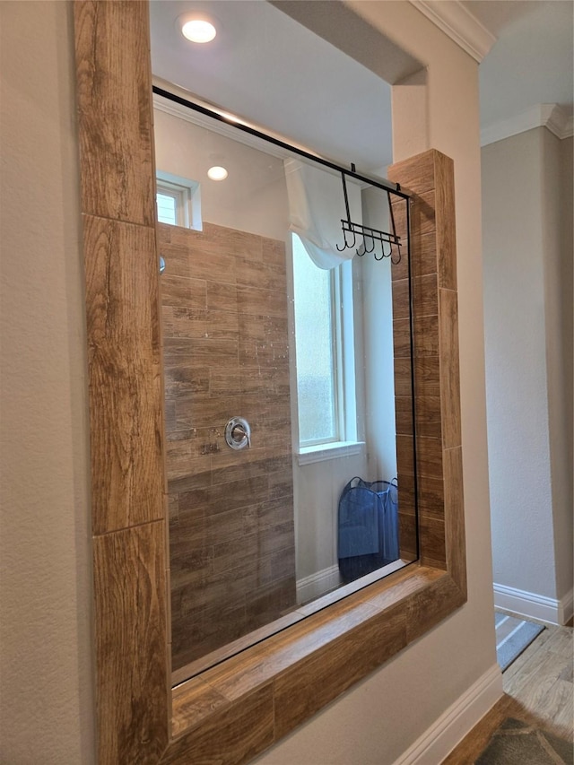 bathroom with ornamental molding, tiled shower, and wood-type flooring