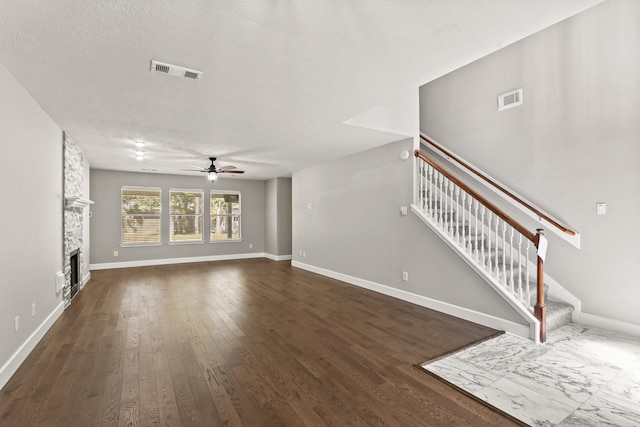 unfurnished living room with a fireplace, ceiling fan, and dark hardwood / wood-style floors