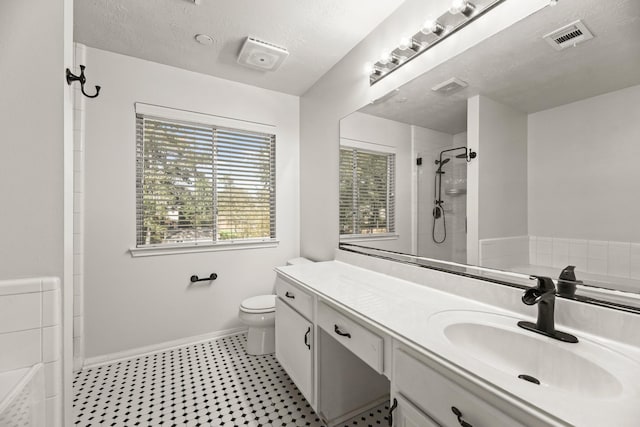 bathroom featuring vanity, tiled shower, toilet, and a textured ceiling