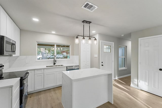 kitchen with stainless steel appliances, white cabinets, pendant lighting, and sink