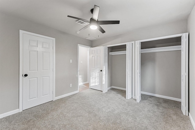 unfurnished bedroom featuring ceiling fan, light carpet, and multiple closets