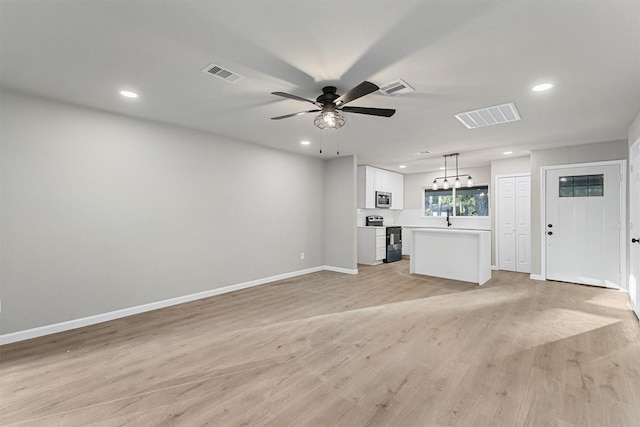 unfurnished living room with sink, ceiling fan, and light hardwood / wood-style floors