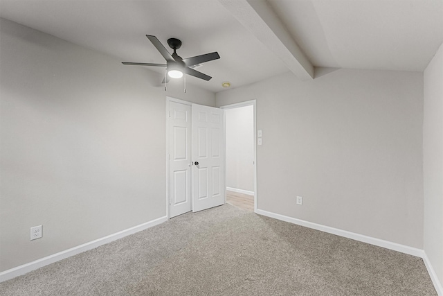 unfurnished room featuring ceiling fan, lofted ceiling with beams, and carpet flooring