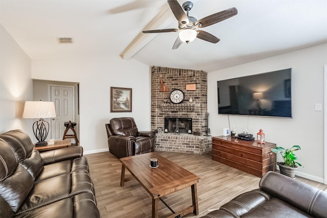 living room with ceiling fan, a brick fireplace, hardwood / wood-style floors, and vaulted ceiling with beams