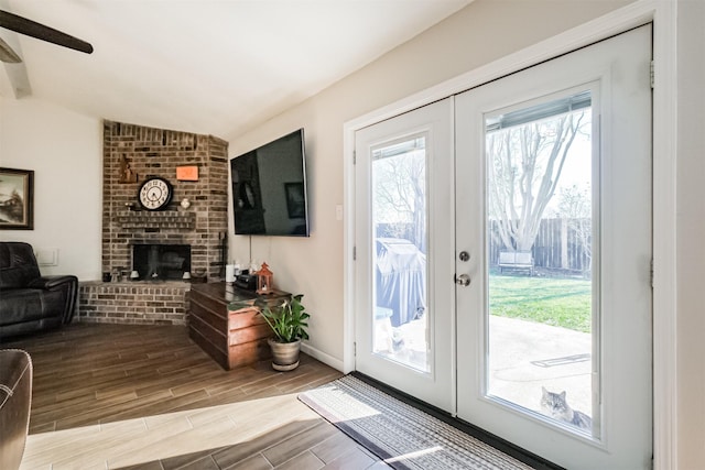 entryway featuring lofted ceiling, french doors, a brick fireplace, and ceiling fan