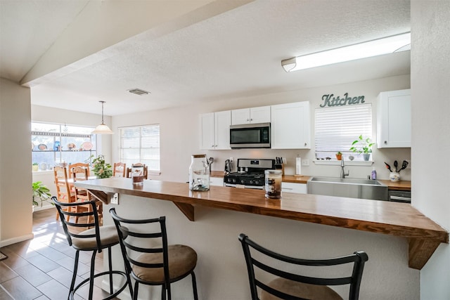 kitchen featuring sink, stainless steel appliances, wooden counters, and white cabinetry