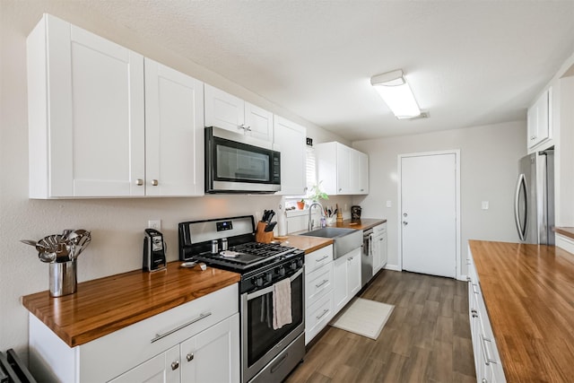 kitchen featuring sink, butcher block countertops, white cabinetry, and appliances with stainless steel finishes