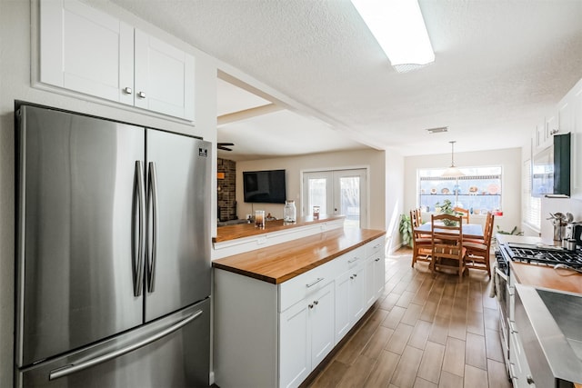 kitchen with decorative light fixtures, white cabinets, plenty of natural light, and appliances with stainless steel finishes