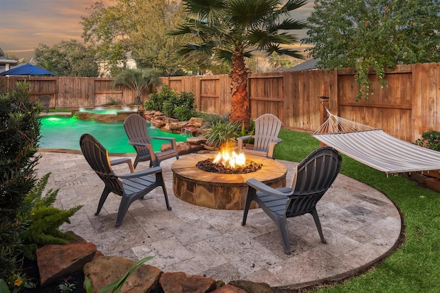 patio terrace at dusk featuring a fire pit and a fenced in pool