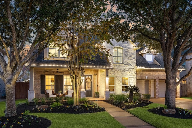 view of front of house featuring a porch, ceiling fan, a garage, and a front yard