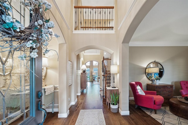 entryway with a high ceiling, ornamental molding, and wood-type flooring