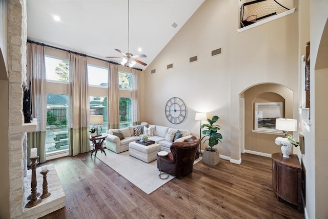 living room with a towering ceiling, wood-type flooring, and ceiling fan