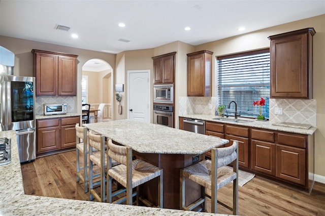 kitchen featuring appliances with stainless steel finishes, hardwood / wood-style floors, backsplash, and sink