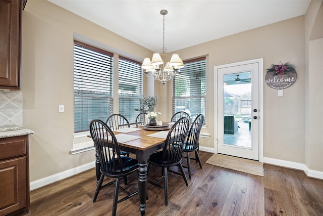 dining space featuring dark wood-type flooring and an inviting chandelier