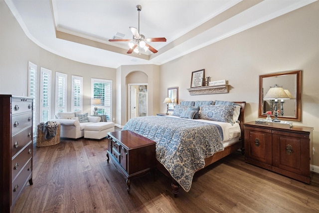 bedroom featuring dark hardwood / wood-style flooring, ceiling fan, a tray ceiling, and ornamental molding