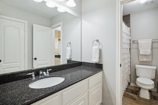 bathroom featuring toilet, walk in shower, and vanity