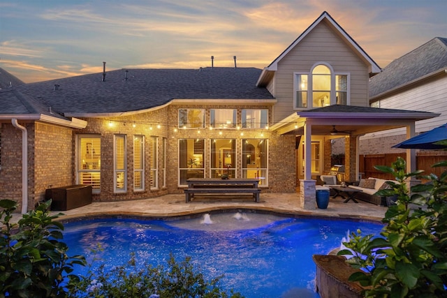 back house at dusk featuring a balcony, ceiling fan, an outdoor hangout area, and a patio