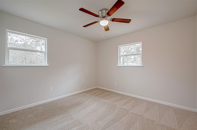 carpeted empty room with ceiling fan and plenty of natural light