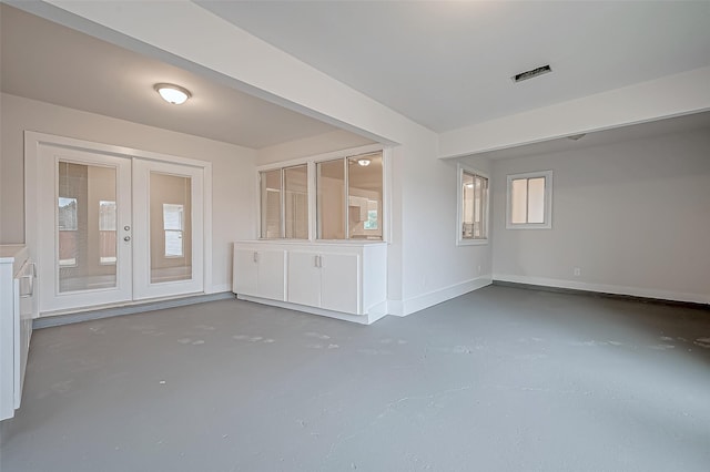 unfurnished living room featuring french doors and concrete flooring