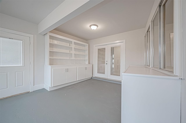 interior space featuring french doors, concrete floors, built in features, and beamed ceiling