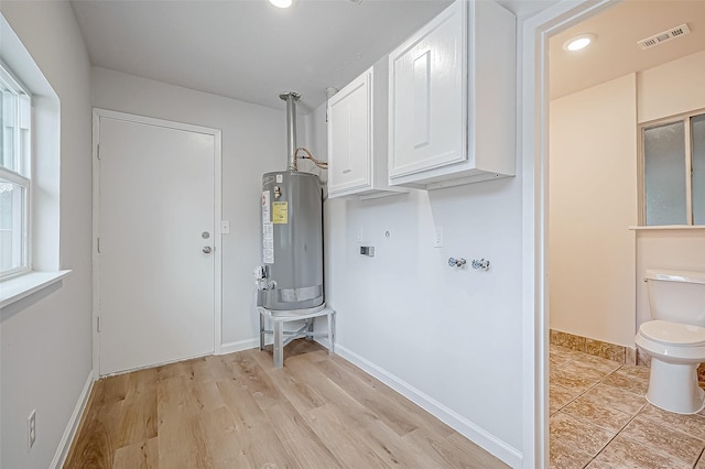 clothes washing area featuring water heater, light hardwood / wood-style flooring, and washer hookup