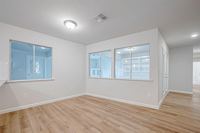 empty room featuring a textured ceiling and light hardwood / wood-style flooring