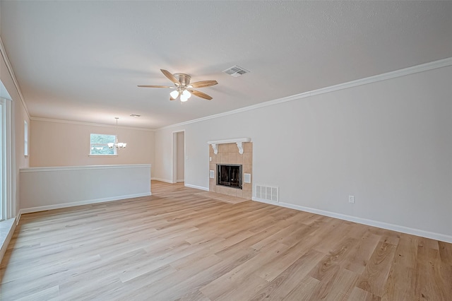 unfurnished living room with a tiled fireplace, light hardwood / wood-style floors, crown molding, and ceiling fan with notable chandelier