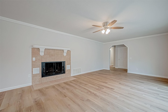 unfurnished living room featuring a tile fireplace, ornamental molding, ceiling fan, and light hardwood / wood-style flooring