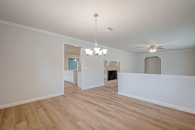 unfurnished room featuring light hardwood / wood-style flooring, a tile fireplace, crown molding, and ceiling fan with notable chandelier