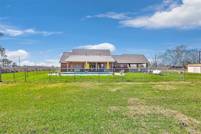 rear view of house with brick siding, a lawn, fence, and a fenced in pool