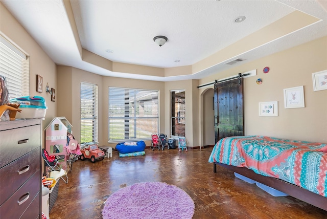 bedroom with a barn door, concrete floors, visible vents, and a raised ceiling