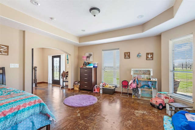 bedroom featuring arched walkways, concrete floors, and baseboards