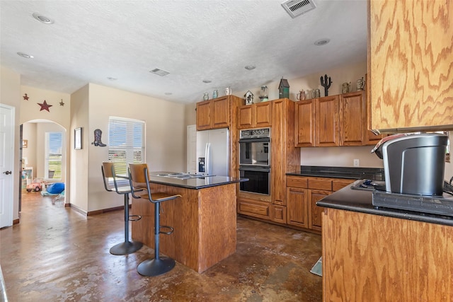 kitchen with stainless steel appliances, dark countertops, visible vents, and a center island