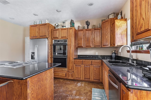 kitchen featuring a center island, visible vents, appliances with stainless steel finishes, brown cabinetry, and a sink