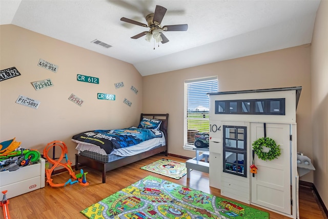 bedroom featuring visible vents, baseboards, ceiling fan, vaulted ceiling, and light wood-style floors