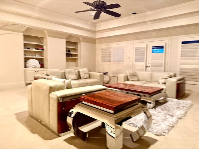 cinema room with ceiling fan, ornamental molding, a raised ceiling, and built in shelves