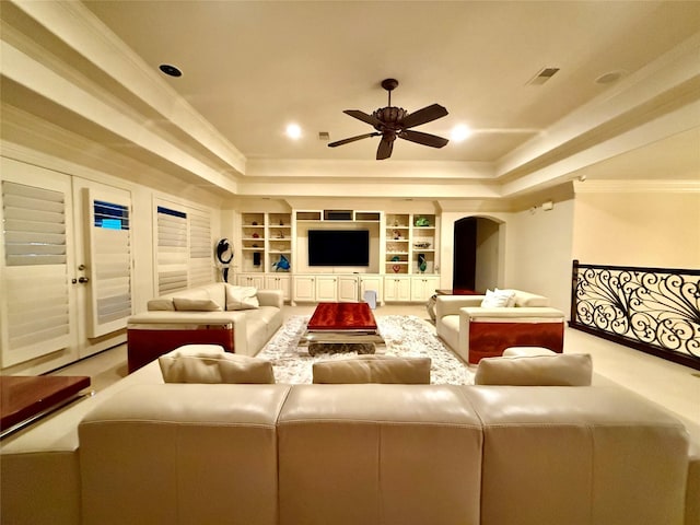 living room with ceiling fan, crown molding, and built in shelves