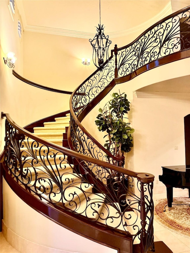 staircase with a towering ceiling, tile patterned flooring, and ornamental molding