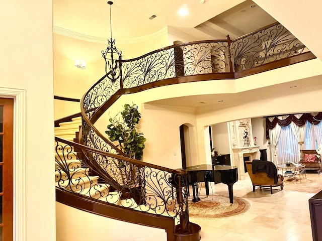 staircase with a towering ceiling and ornamental molding