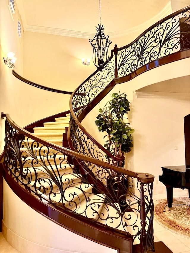 staircase featuring a towering ceiling, crown molding, and tile patterned floors