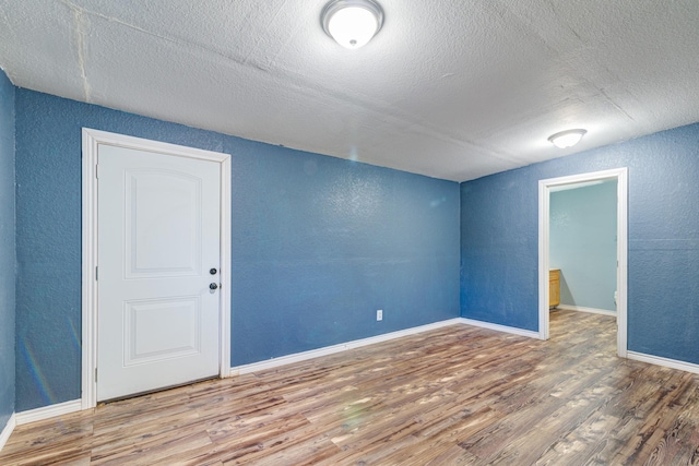 unfurnished room with a textured ceiling and hardwood / wood-style floors