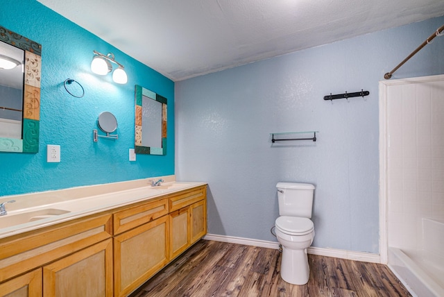 bathroom with toilet, hardwood / wood-style flooring, walk in shower, and vanity