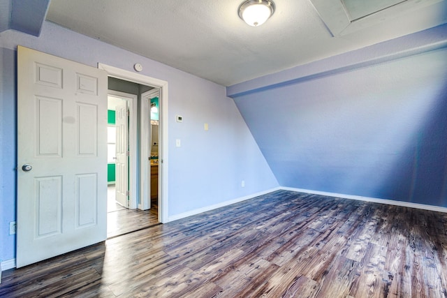 unfurnished room featuring lofted ceiling, a textured ceiling, and dark hardwood / wood-style flooring