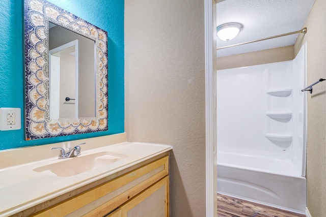 bathroom featuring a textured ceiling, bathtub / shower combination, vanity, and wood-type flooring