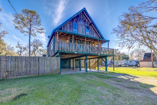 rear view of house with a patio, a lawn, and a wooden deck