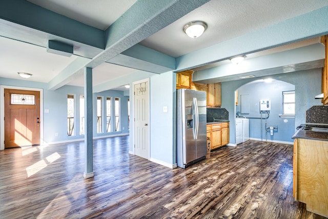 kitchen with dark wood-type flooring, a textured ceiling, stainless steel refrigerator with ice dispenser, and decorative backsplash