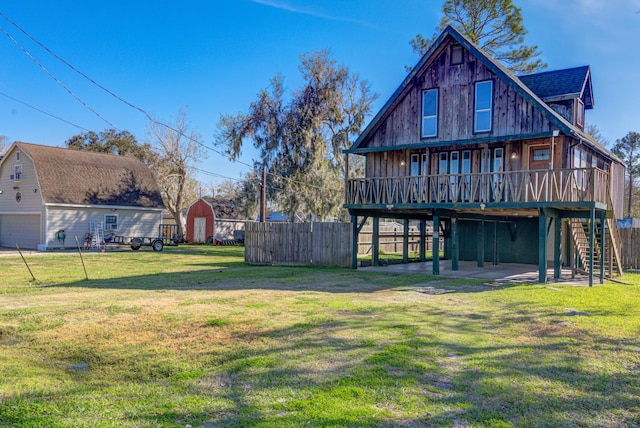 rear view of house featuring a deck, a yard, and a storage shed